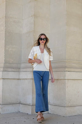 a lady wears a white knitted top with flared jeans